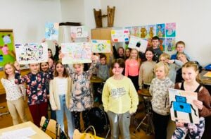 Kuvassa koululaisia jotka pitävät käsissään piirrustuksia Rauhankoneen prototyyppi-piirustuksia