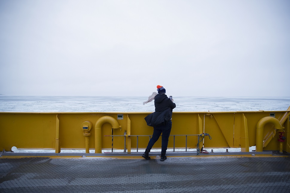 A woman standing on a moving ferry in the winter