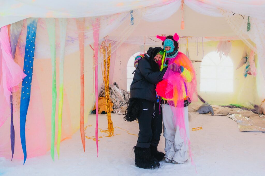 Colorful tent interior with two people hugging.