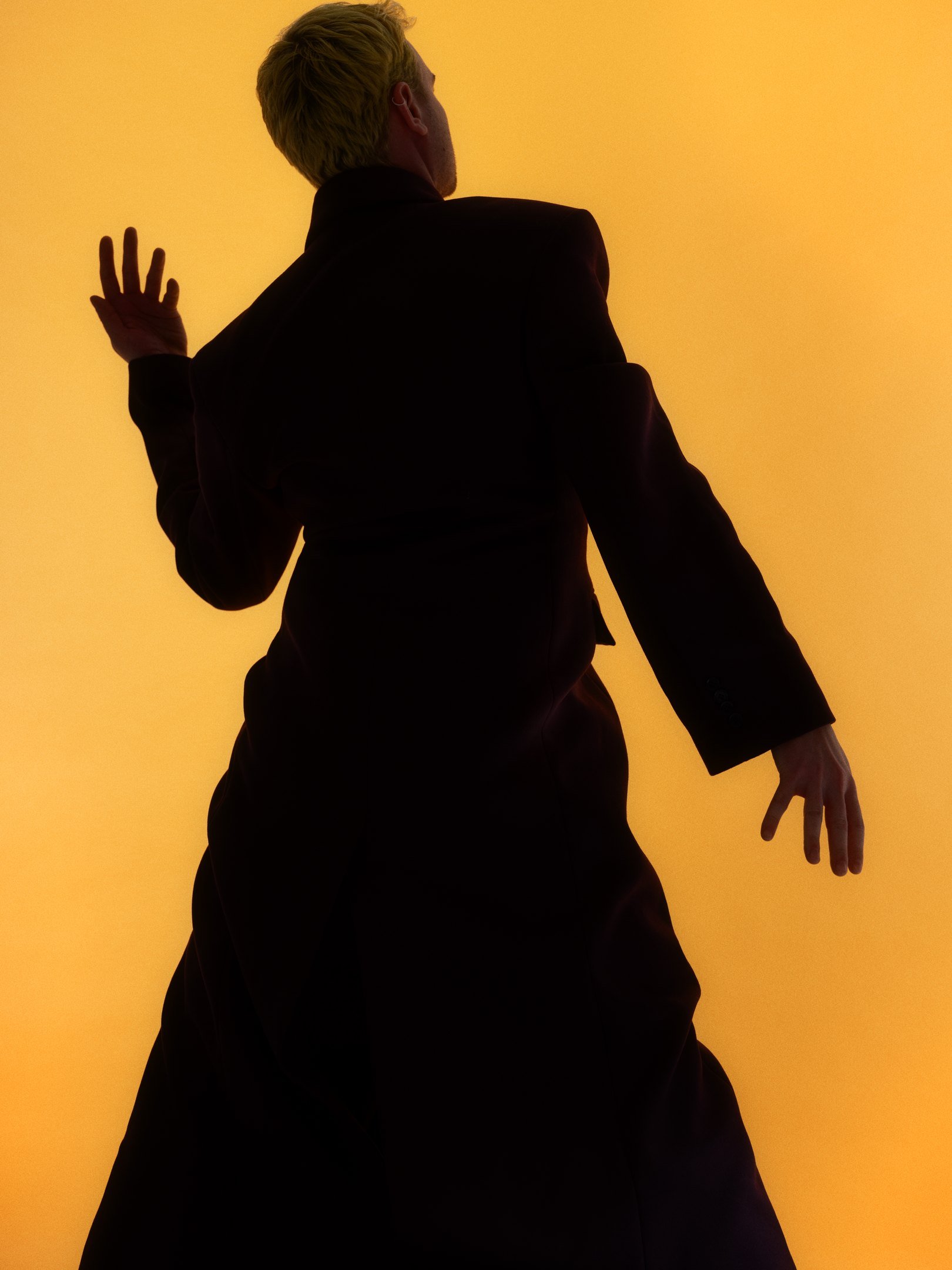 Hahmo tummaa taustaa vasten oranssissa valossa.