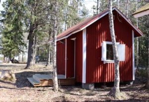 kuvassa punainen pieni mökki metsässä