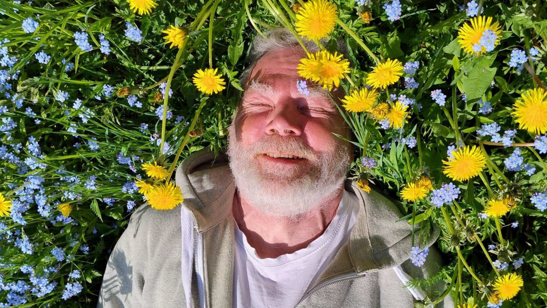 Kirjailija Klaus Rahikainen kesäisellä voikukkaniityllä. Kuva: Marius Elding.