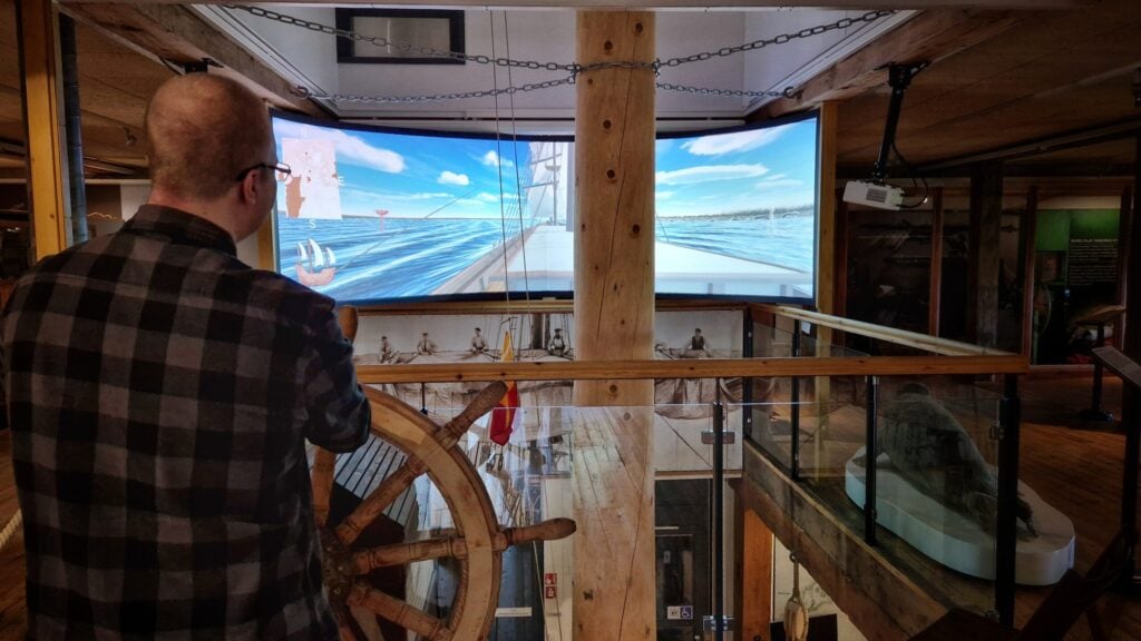 Visitor steering a sailing ship towards Raahe roadsted, using a real ship´s wheel. PIcture: Anna Latomaa/Raahen museo
