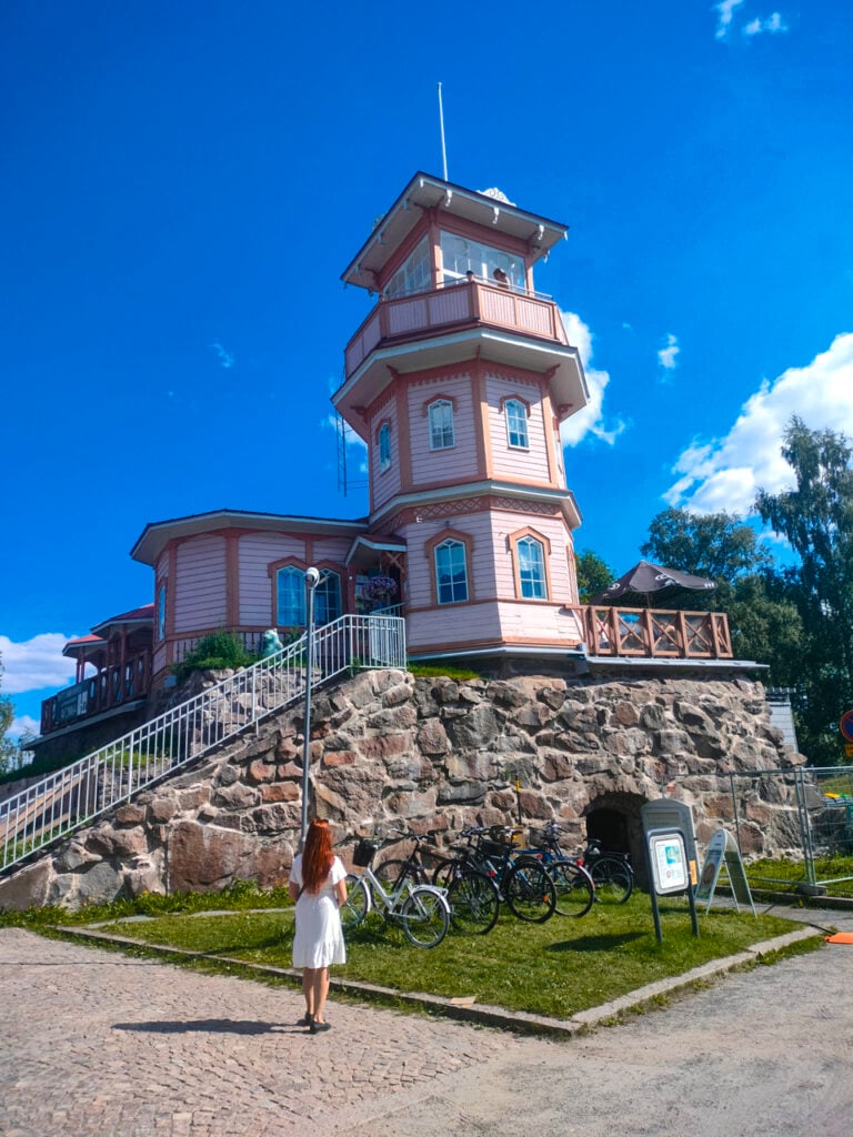 Historic pink tower with visitor on sunny day.
