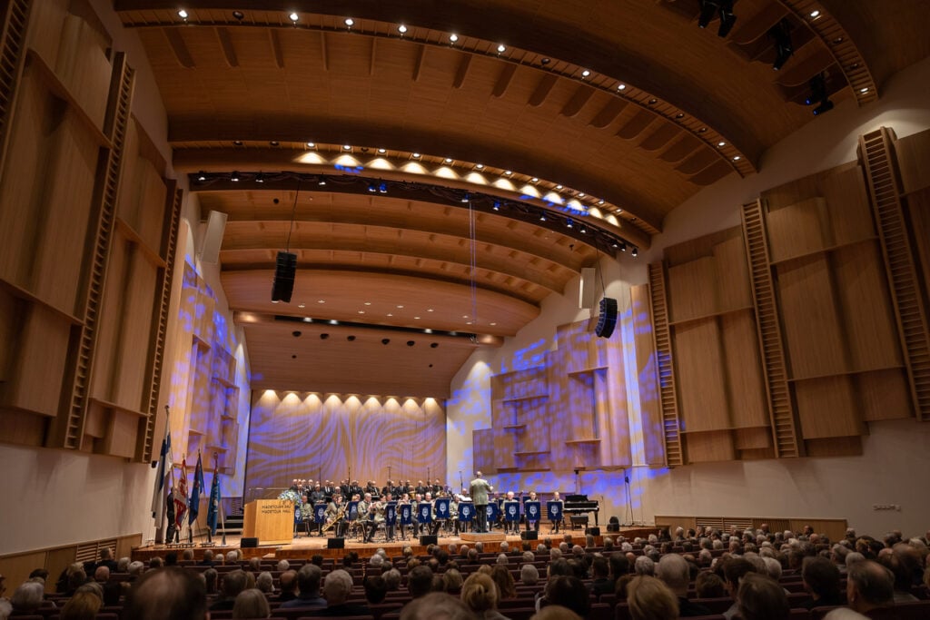 Concert hall with audience and orchestra on stage.