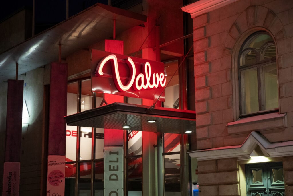 Neon 'Valve' sign on building at night.