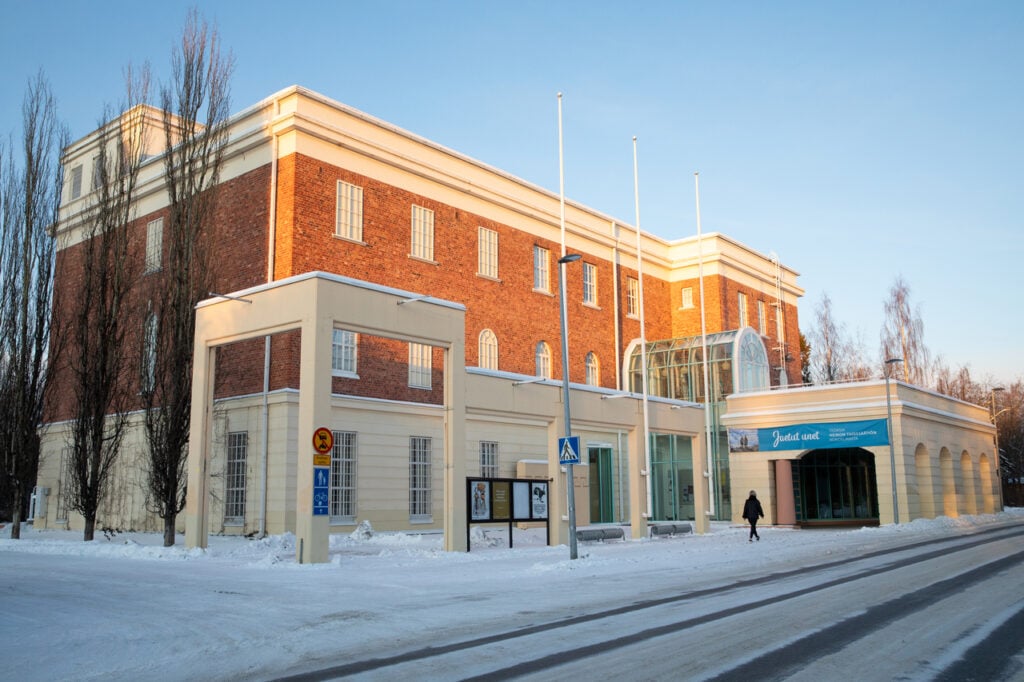 Red-brick building with snow-covered surroundings in winter.