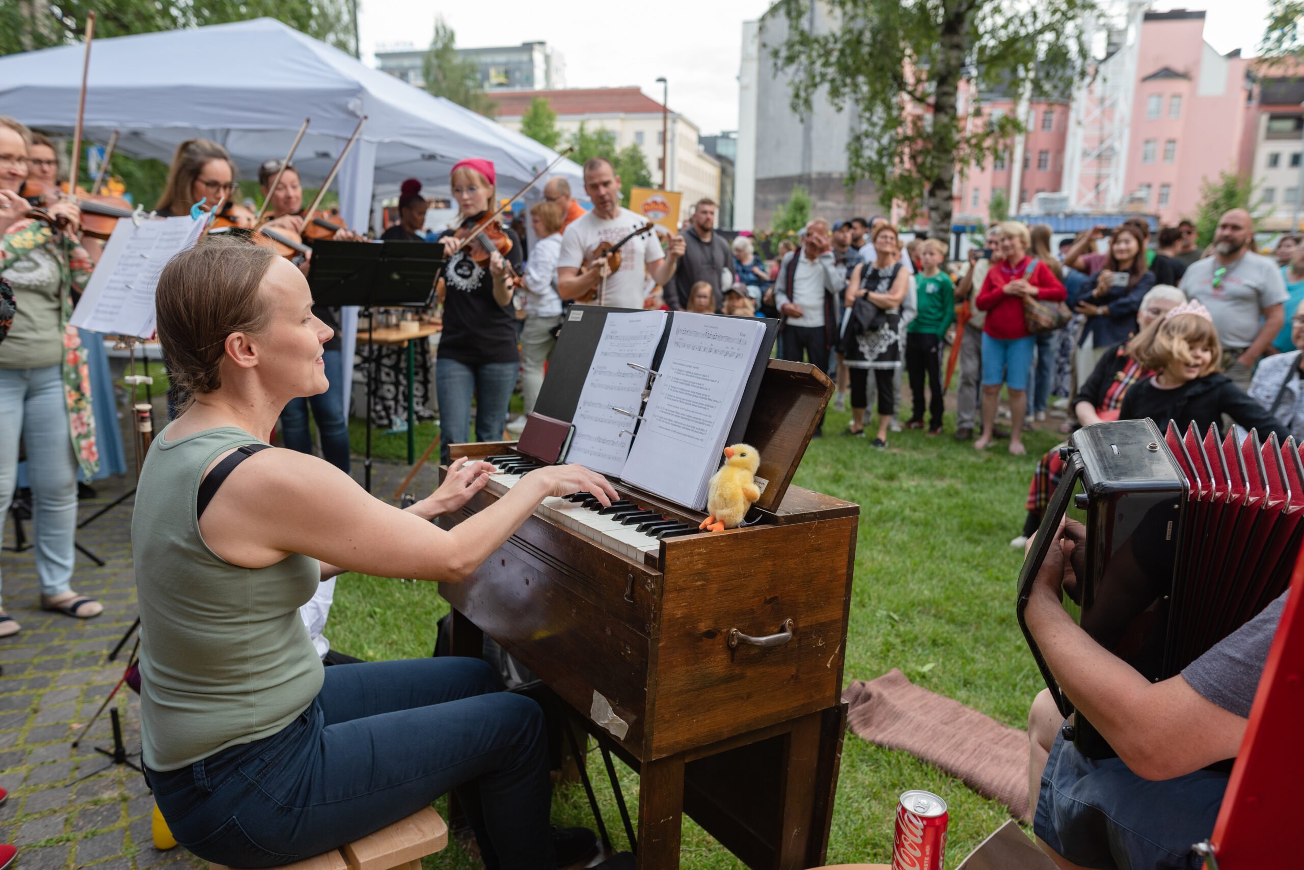 Kuvassa pelimannikollektiivi Orivesi All Stars esiintyy Kesäillan kattaus -tapahtumassa Oulun keskustassa. Ympärillä iloinen yleisö.