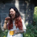 Woman eating a cinnamon bun and drinking coffee outside in Finland in the summer.