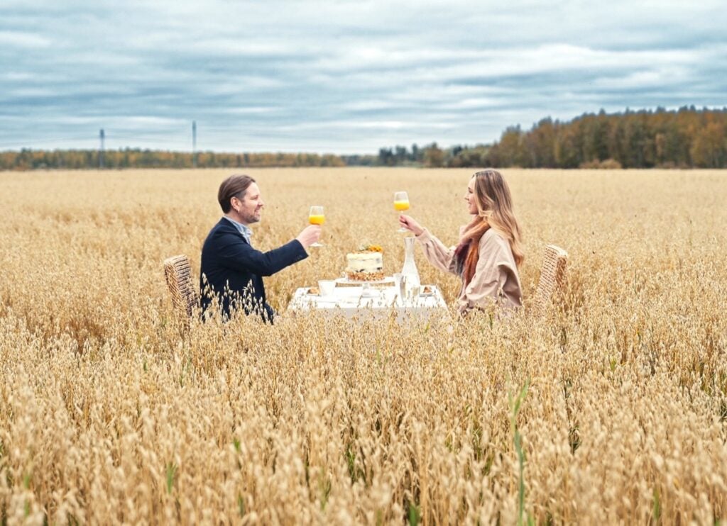 kuvassa kaksi ihmistä istuu keskellä peltoa pöydän ympärillä