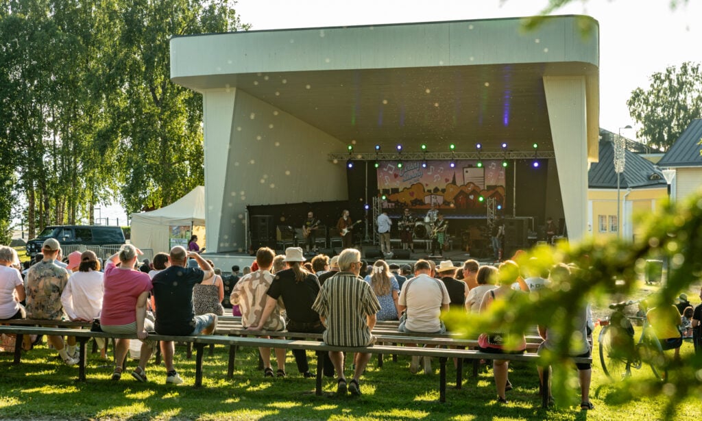 Ihmiset seuraamassa musiikkiesitystä ulkolavalla.